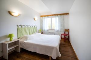a bedroom with a white bed and a window at Gîte Des Myrtilles in Le Soulié