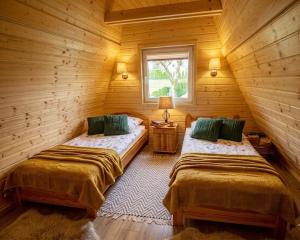 two beds in a log cabin with a window at Bieszczadzki Reset A-Frame in Bukowiec