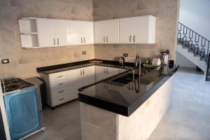 a kitchen with white cabinets and a black counter top at Azure Guest House in Luxor
