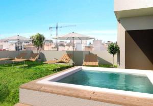 a swimming pool with chairs and umbrellas on a building at Apartamento Lujoso Centro Torrevieja in Torrevieja