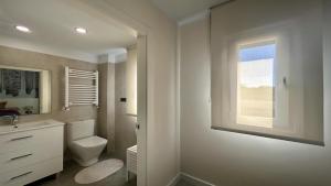 a white bathroom with a toilet and a window at LAS QUINTAS DE BRICIA 6-B in Posada de Llanes