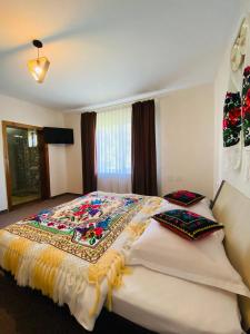 a bedroom with a bed with a colorful blanket on it at Pensiunea Casa Mariuca in Văleni