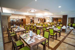 a restaurant with wooden tables and green chairs at Wellness Hotel Gyula in Gyula