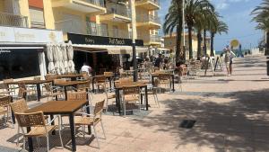 an outdoor cafe with tables and chairs and palm trees at On the Beach Oliva in Oliva
