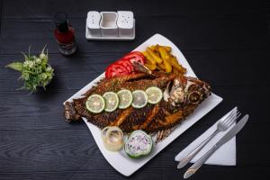 a plate of fish and vegetables on a table at The Gray Haven Lakeside Condo in Entebbe in Entebbe