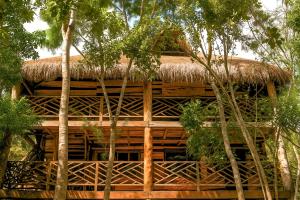a bamboo house with a thatched roof and trees at Treehouse Tulum H2Ojos in Tulum