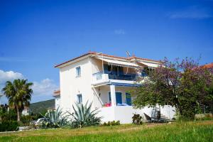 a white house with a balcony and palm trees at Candia Relax House in Kandia