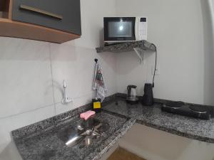 a kitchen counter with a sink and a tv on the wall at Casa completa - Ótimo Custo-benefício in Itajaí