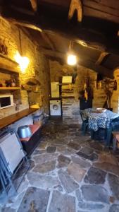 a room with a stone floor with a table and a stove at Casa Venancio in Trabada
