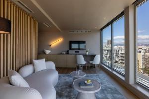 a living room with white furniture and large windows at Golden Age Athens Hotel in Athens