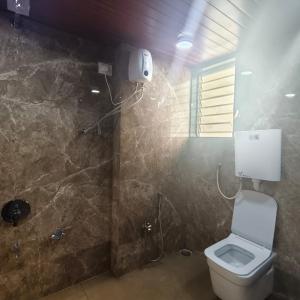 a bathroom with a toilet and a stone wall at Sai Srushti Residency in Kalyan +37 photos