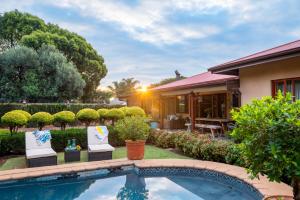 a house with a swimming pool in front of a yard at Hampton House Guest House in Centurion