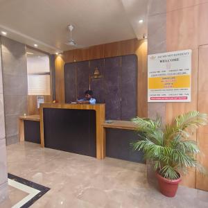 a man sitting at a reception desk in a lobby at Sai Srushti Residency in Kalyan