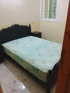 a bedroom with a bed with a green comforter at Zerarda in Saïss