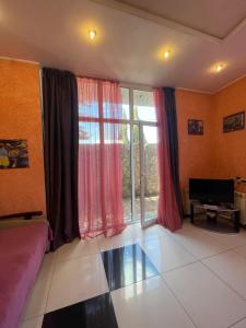 a living room with a large window with red curtains at Тownhouse99 in Petropavlovskaya Borshchagovka