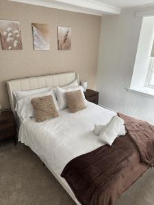 a bedroom with a large bed with white sheets and pillows at Towerknowe in Hawick