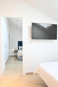 a white bedroom with a flat screen tv on the wall at Šangulin Palace M in Biograd na Moru