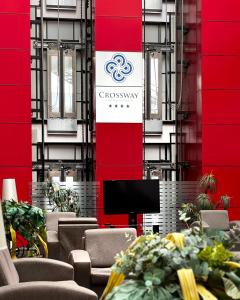 a room with chairs and a tv and a red wall at Crossway Hotel Baku in Baku