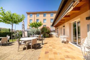 a patio with tables and chairs and a building at Best Western Hôtel Le Sud in Manosque