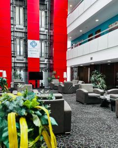 a lobby with couches and plants in a building at Crossway Hotel Baku in Baku