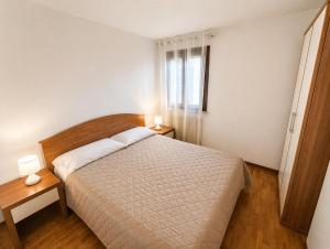 a bedroom with a bed and two tables and a window at La Casa del Mare in Caorle +3 photos