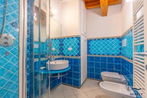 a blue tiled bathroom with a sink and a toilet at Casa Corallina in Olbia +21 photos