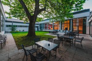 a patio with tables and chairs and a tree at Bildungshaus St. Hippolyt in Sankt Pölten