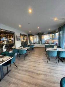 a restaurant with blue tables and chairs and windows at Strandhotel Deichläufer in Butjadingen
