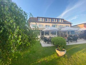 a building with tables and umbrellas in a yard at Strandhotel Deichläufer in Butjadingen