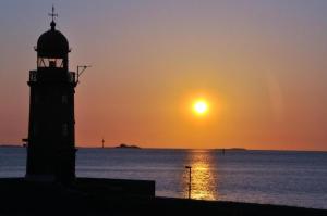 a lighthouse with the sunset in the background at Strandhotel Deichläufer in Butjadingen +14 photos