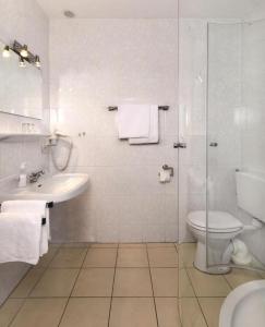 a white bathroom with a toilet and a sink at Strandhotel Deichläufer in Butjadingen