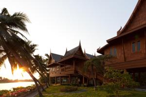 une grande maison en bois à côté d'un palmier dans l'établissement RK Riverside Resort & Spa (Reon Kruewal), à Ban Khlong Krang