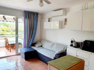 a living room with a blue couch and a kitchen at T2 les pieds dans l eau avec piscine in San-Nicolao