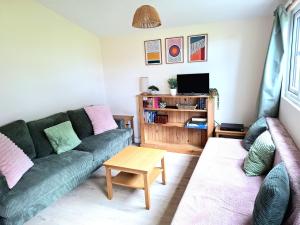 a living room with a green couch and a table at Cosy Corner Cabin in Saint Merryn