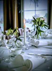 a white table with a candle and plates and glasses at Hotell Nostalgi in Motala