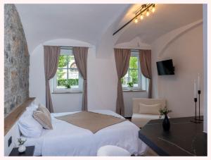 a bedroom with a bed and a desk and two windows at The 1826 Residence in Ljubljana