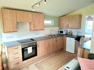 a kitchen with wooden cabinets and a stove top oven at Cosy Corner Cabin in Saint Merryn