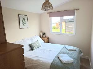 a bedroom with a white bed and a window at Cosy Corner Cabin in Saint Merryn
