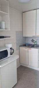 a kitchen with white cabinets and a microwave at Sackle's place in Pori