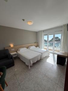 a bedroom with a bed and a couch and a window at Hotel Riveiro in Sanxenxo