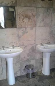 a bathroom with two white sinks and a mirror at Pop Lamont Camp in Chobe