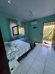 a bedroom with a bed with blue walls and a window at Chalé da jessica in Paraty