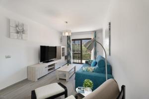 a living room with a blue couch and a tv at Adelfa Golf in San Miguel de Abona