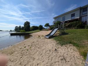 a playground on a beach next to a building at Ferienwohnung Natursjæl in Tielen