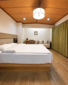 a bedroom with a large white bed and wooden ceilings at Kurmon Inn in Omachi