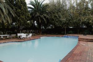 a large swimming pool with a table and chairs at The Hidden Garden Guesthouse in Meyerton