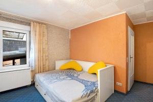 a bedroom with a bed with yellow pillows and a window at Familienhaus mit riesigem Garten in Arnsdorf