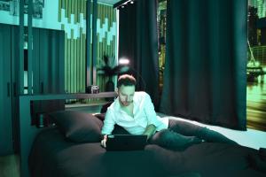 a man sitting on a bed using a laptop at Chambre business-romantique, jacuzzi, billard, clim in Verviers