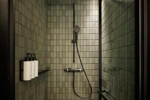 a shower in a bathroom with white tile walls at Caption By Hyatt Kabutocho Tokyo in Tokyo +50 photos