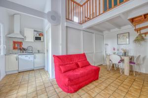 a living room with a red couch and a kitchen at Lacanau Océan avec jardin in Lacanau-Océan +16 photos